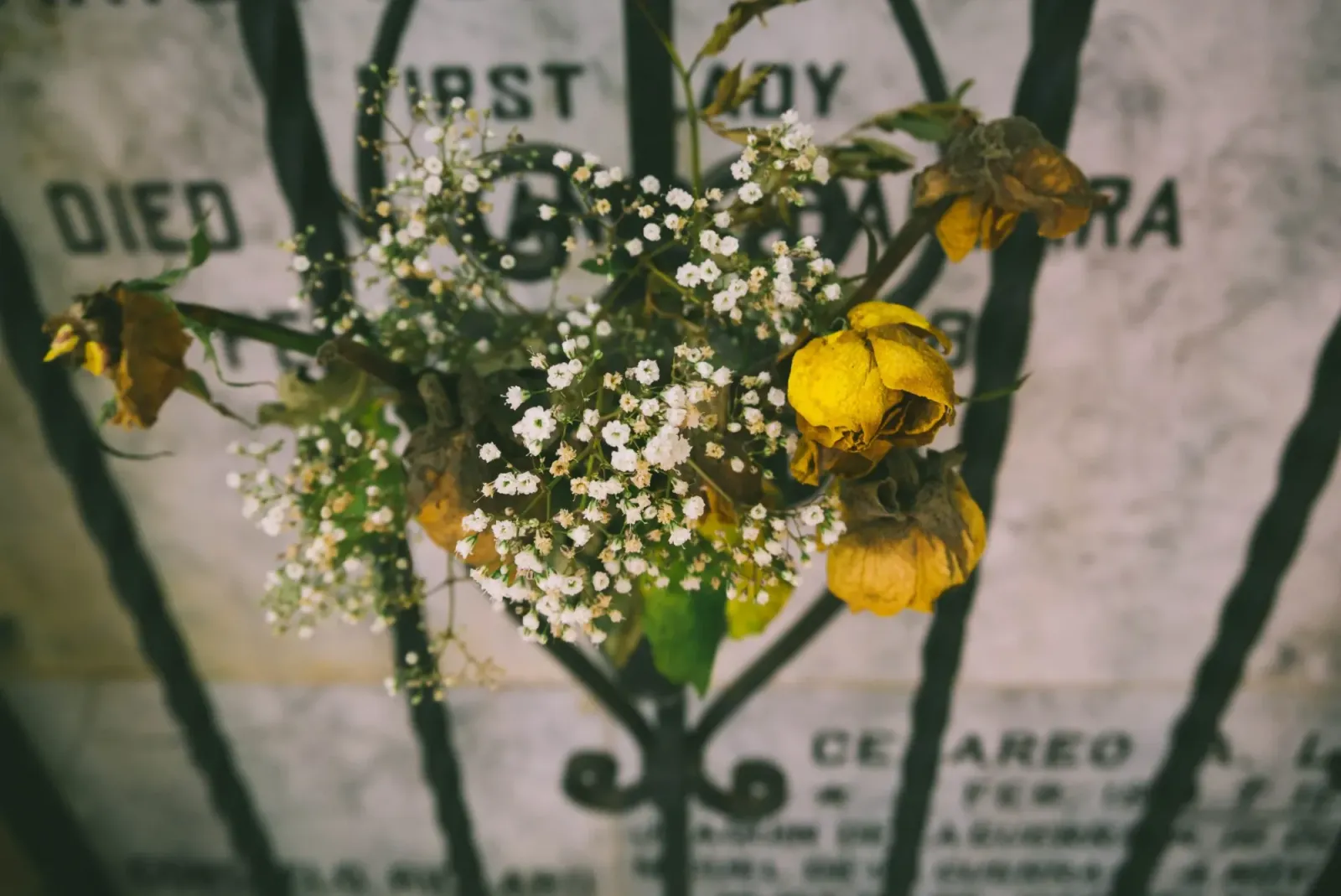 A bouquet of wilted yellow roses and small white flowers.