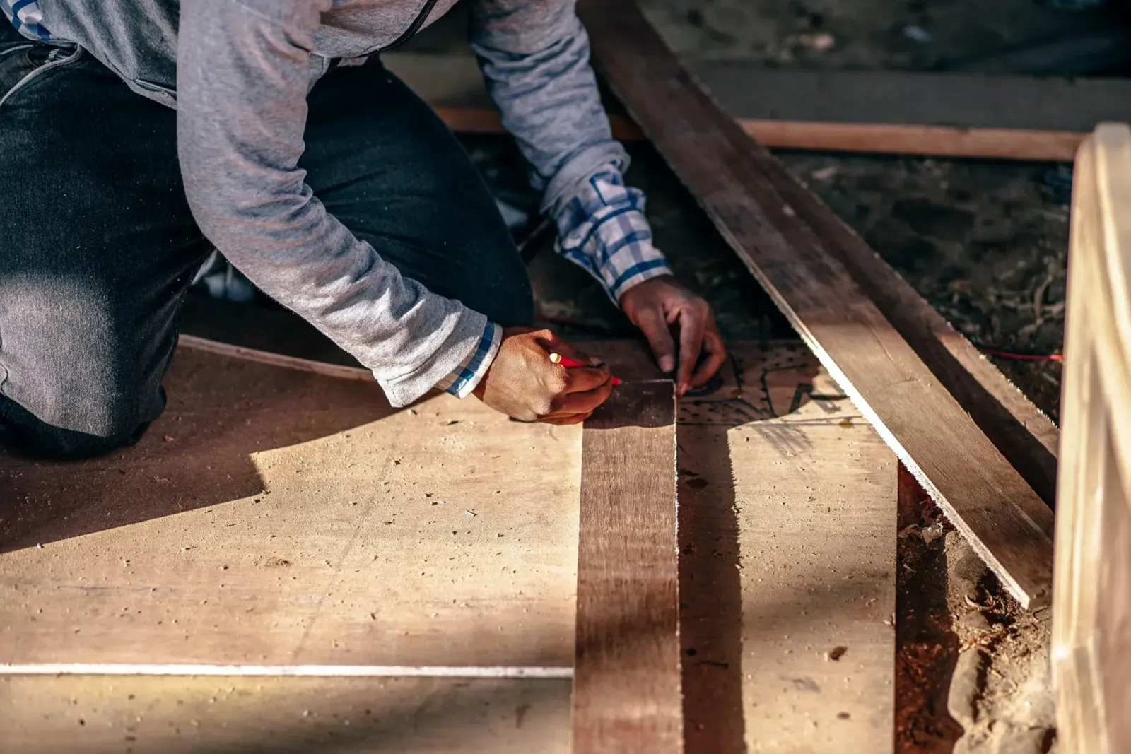 A person marking a wooden board with a pencil.