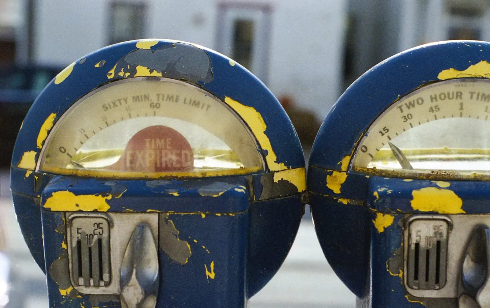 Two weathered blue-and-yellow parking meters.