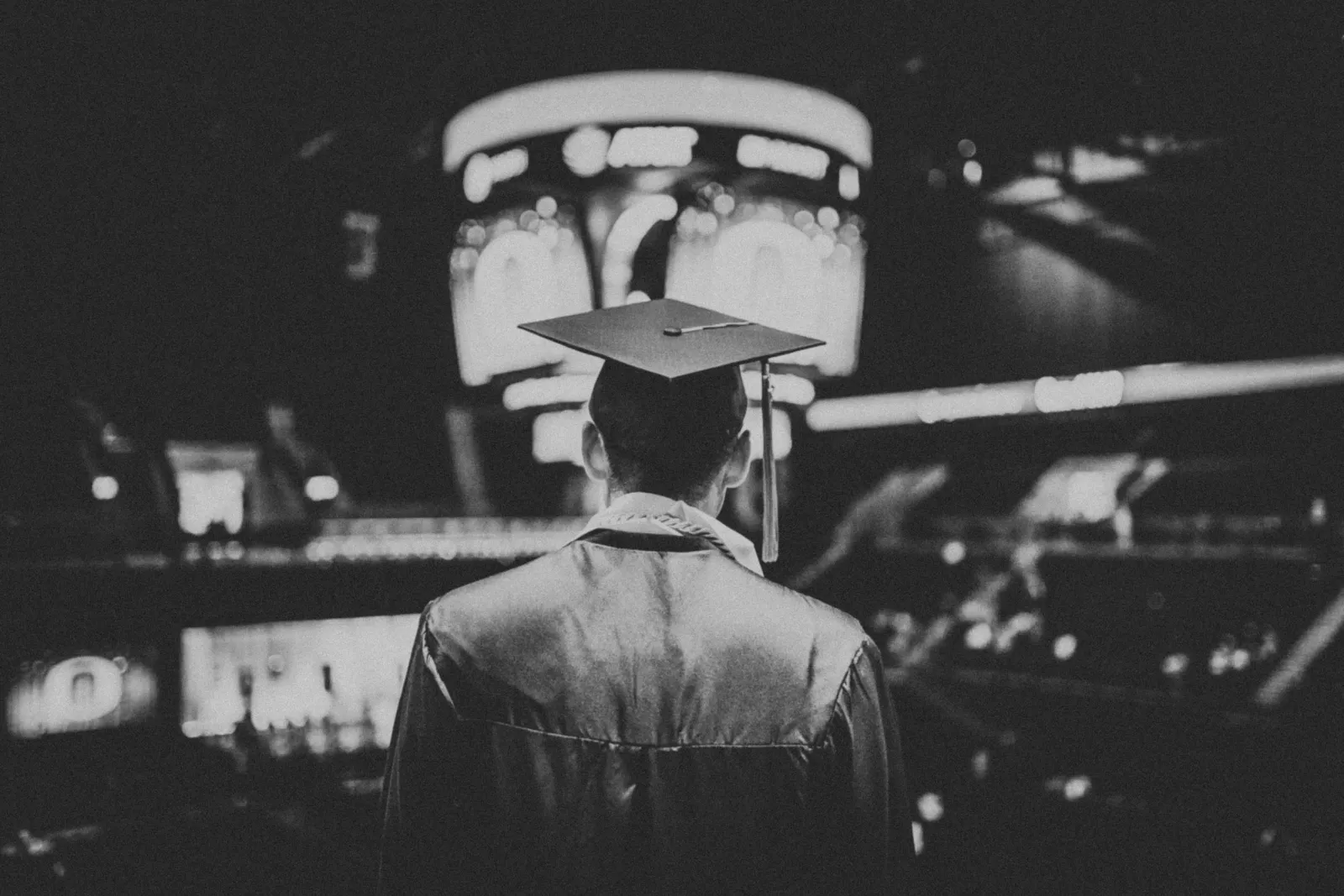 Graduate wearing a cap and gown, viewed from behind.